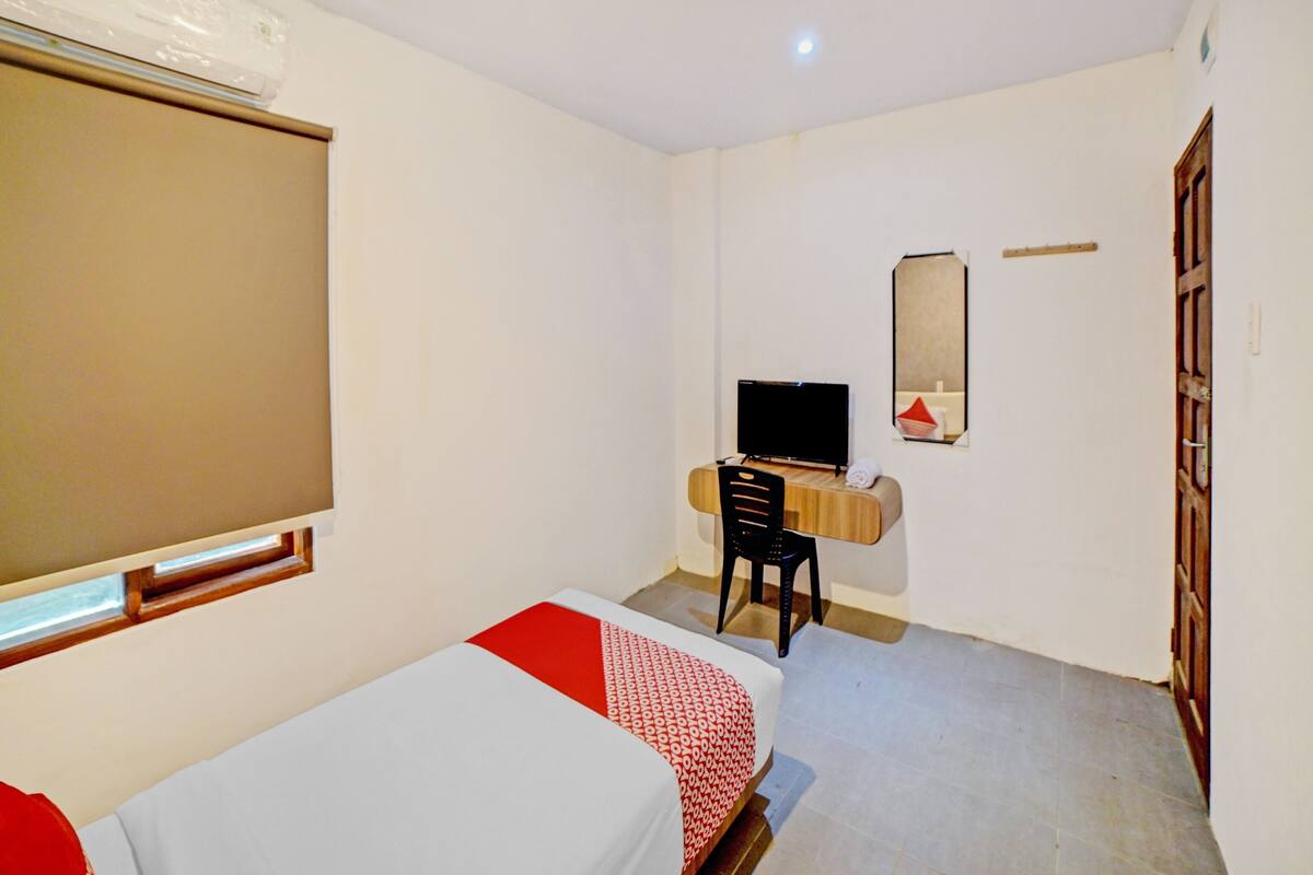 A room with two beds, a desk with a chair, a TV, a mirror, and a window.