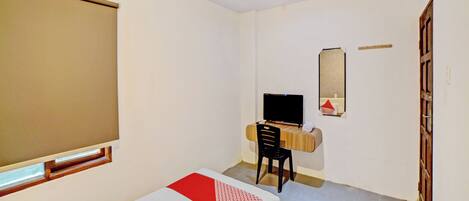 A hotel room with two beds, a desk with a computer, a mirror, and a window.
