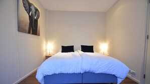 A bedroom with a large bed, two bedside lamps, and a painting on the wall. - Rural holiday home with terrace (Zuidwolde)