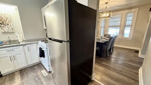 Moderni keittiö, jossa on valkoiset kaapit, ruostumattomasta teräksestä valmistettu jääkaappi ja kaasuliesi.