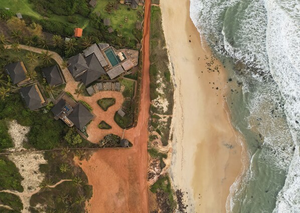 An aerial view of a coastal property with a beach, a swimming pool, and several houses. - Filha da Lua Ecolodge (Tibau do Sul)