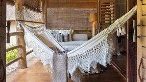 Un hamac dans une pièce en bois, avec un toit de chaume et une suspension lumineuse.