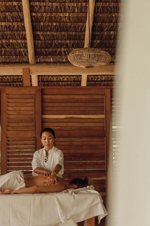 A massage therapy session in a room with wooden shutters and a thatched roof. - Filha da Lua Ecolodge (Tibau do Sul)