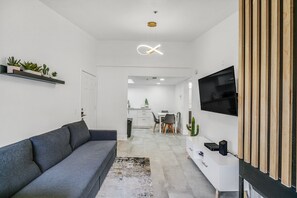 Relax in this stylish living space with a sofa, entertainment unit, and dining area.