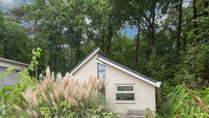 Une petite maison avec un toit en pente, une fenêtre et un banc devant.