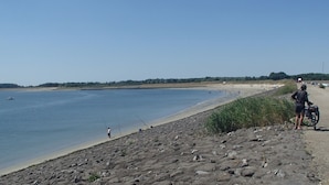 A rocky shoreline with a person fishing and another person standing next to a motorcycle. - Boutique Apartment in Ritthem with Terrace (Vlissingen-Ritthem)