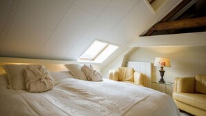 A hotel room with a large bed, a skylight, a sofa, and a lamp. - Boutique Apartment in Ritthem with Terrace (Vlissingen-Ritthem)