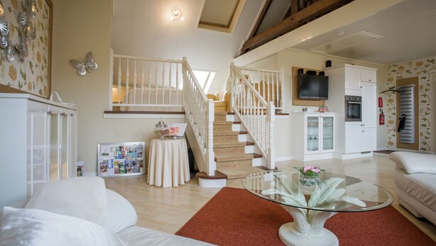 A spacious living area with a staircase, a glass coffee table, and a white sofa. - Boutique Apartment in Ritthem with Terrace (Vlissingen-Ritthem)