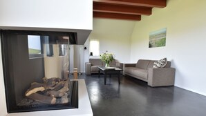 Een moderne woonkamer met een open haard, een bank, een salontafel en een schilderij aan de muur.