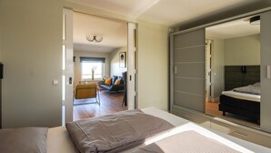 Une chambre moderne avec un grand miroir, une armoire et un canapé dans le salon attenant.