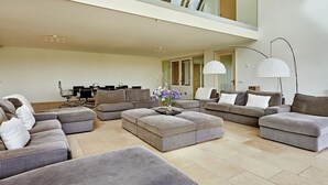 Un ampio soggiorno con diverse zone relax, un'area pranzo e un soffitto alto con finestra a lucernario.