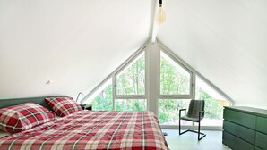 A bedroom with a bed, a chair, and a large window. - Chalet in Reutum with Sauna and Nature (Reutum-Weerselo)