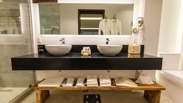 Une salle de bain moderne avec deux lavabos, un grand miroir et une étagère en bois où sont posées des serviettes.