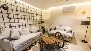A modern living room with two sofas, a wooden cart, patterned wall, and a floor lamp. - Casa Naila Hotel Boutique (Oaxaca)