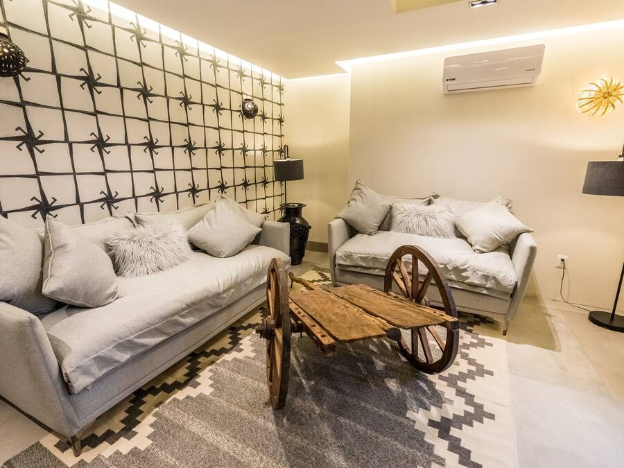 Una sala de estar moderna con dos sofás, un carrito de madera, pared con diseño y una lámpara de pie.