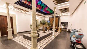 A lobby with a tiled floor, columns, a scooter, and a colorful ceiling. - Casa Naila Hotel Boutique (Oaxaca)