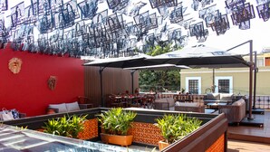 A rooftop bar with a glass-top pool, outdoor seating, and decorative plants. - Casa Naila Hotel Boutique (Oaxaca)