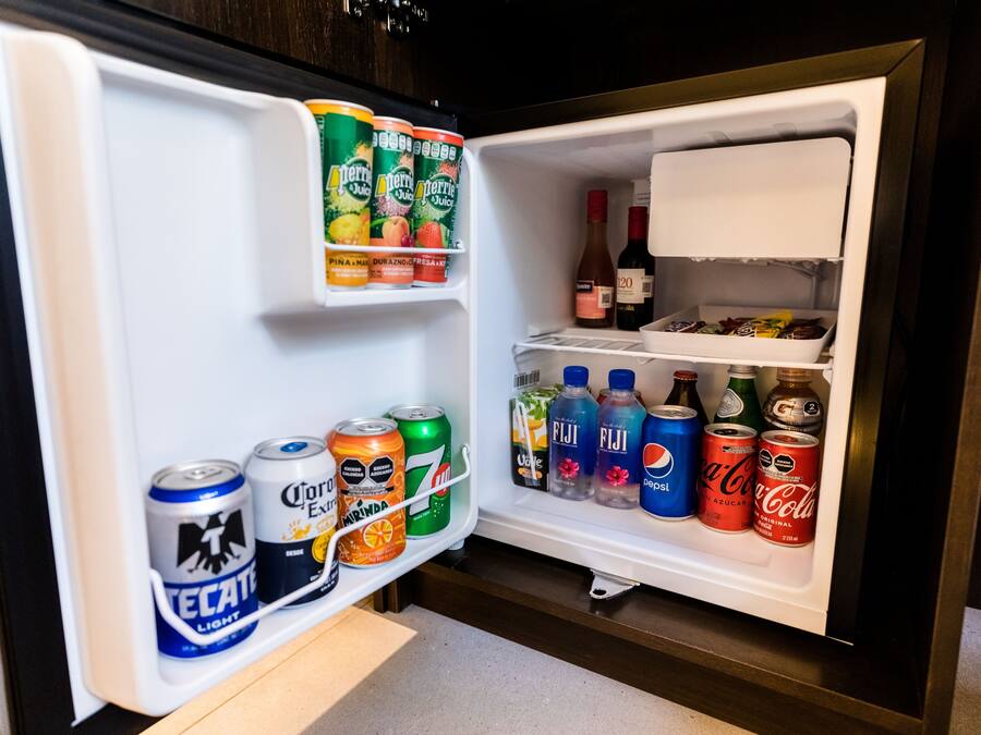 An open refrigerator stocked with various beverages including Perrier, Tecate, Corona, and Fiji.
