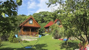 Eine Holzhütte mit rotem Dach, umgeben von üppigem Grün und einem gepflegten Rasen.