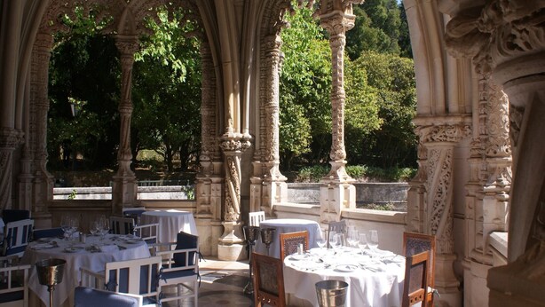 An outdoor dining area with tables set for a meal, surrounded by ornate stone columns and arches. - Idyllic Country Cottage with Forest (Covas)