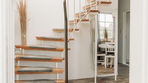 Een modern interieur met een houten trap, een eetgedeelte en uitzicht op de omgeving.