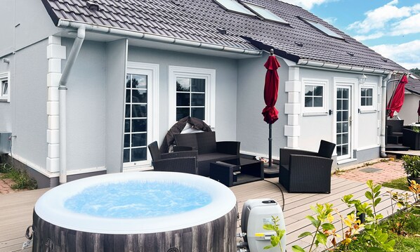 A house with a patio, a hot tub, and outdoor furniture.