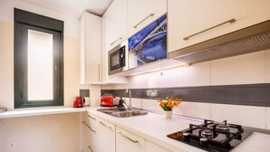 A modern kitchen with white cabinets, a stainless steel sink, a gas stove, a microwave, and a red toaster. - Slava by Sevilla Luxury Suite (Sevilla)