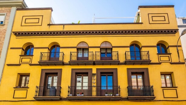A yellow building with multiple balconies and arched windows. - Slava by Sevilla Luxury Suite (Sevilla)