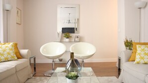 Un soggiorno moderno con due poltrone bianche, un tavolino in vetro con un vaso decorativo e un arredamento dallo stile minimalista.