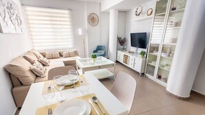 Un salon moderne comprenant un coin repas, un ensemble de canapés, un téléviseur et une vitrine.