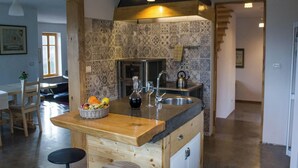 A kitchen with a wooden island, a sink, and a patterned backsplash.