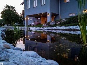 A modern building with a reflective pond, outdoor seating, and a snowy landscape.