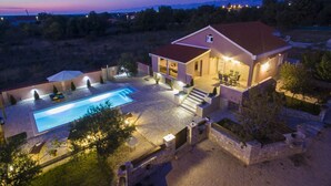 Ein zweistöckiges Haus mit Swimmingpool, Außenbereich zum Sitzen und einer gut beleuchteten Terrasse.