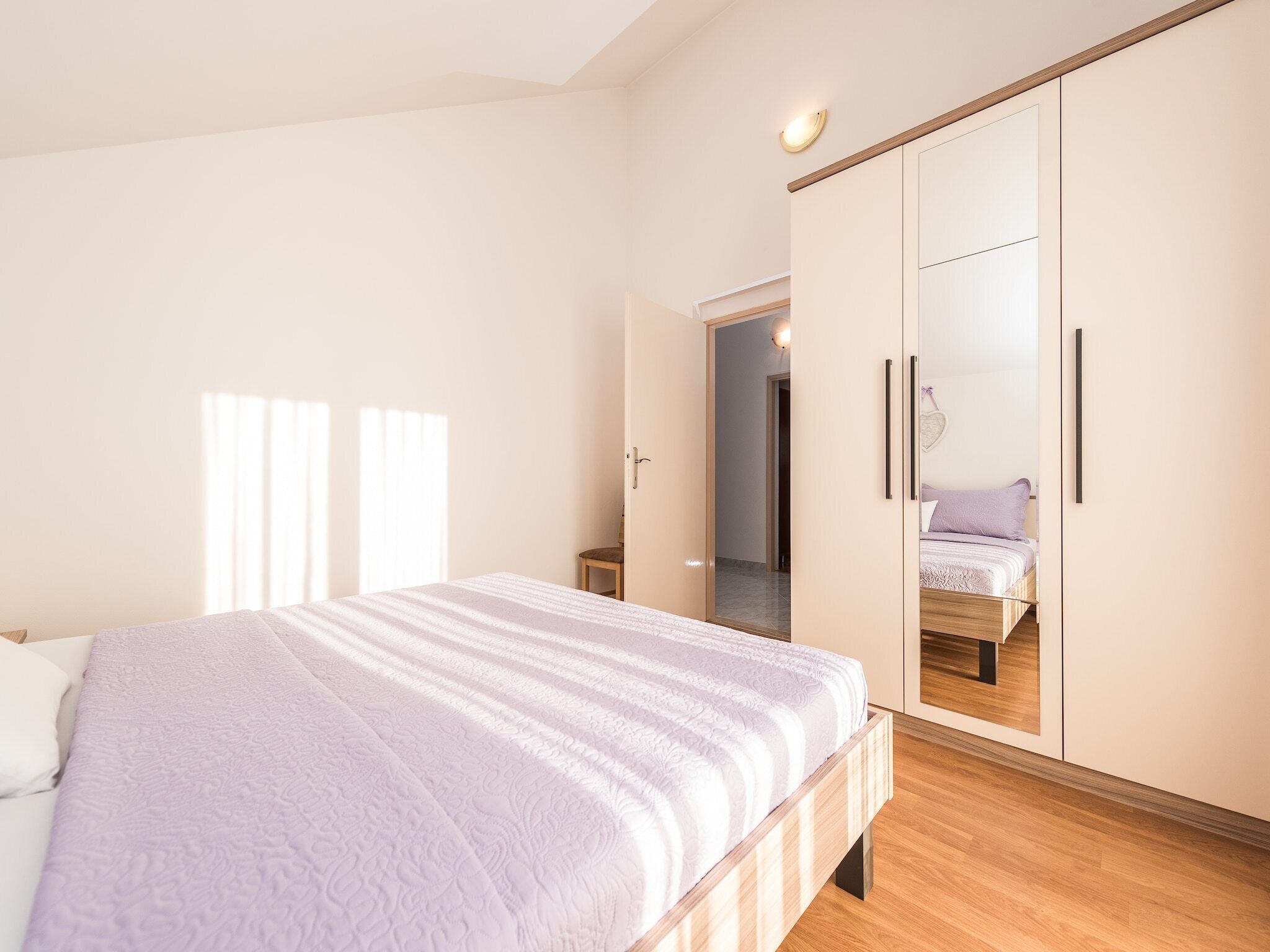 A bedroom with a bed, a wardrobe, and a mirror.