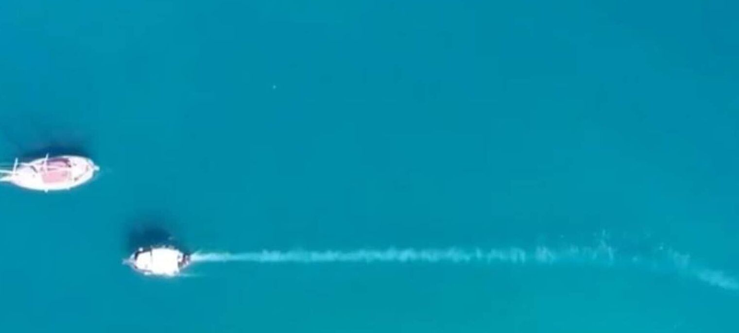 Vista aérea de una masa de agua con un barco dejando una estela.