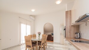 A modern kitchen with a dining area, featuring a marble floor, wooden chairs, and a coffee maker. - Apartment in Vrsi near the Sea (Vrsi-Mulo)