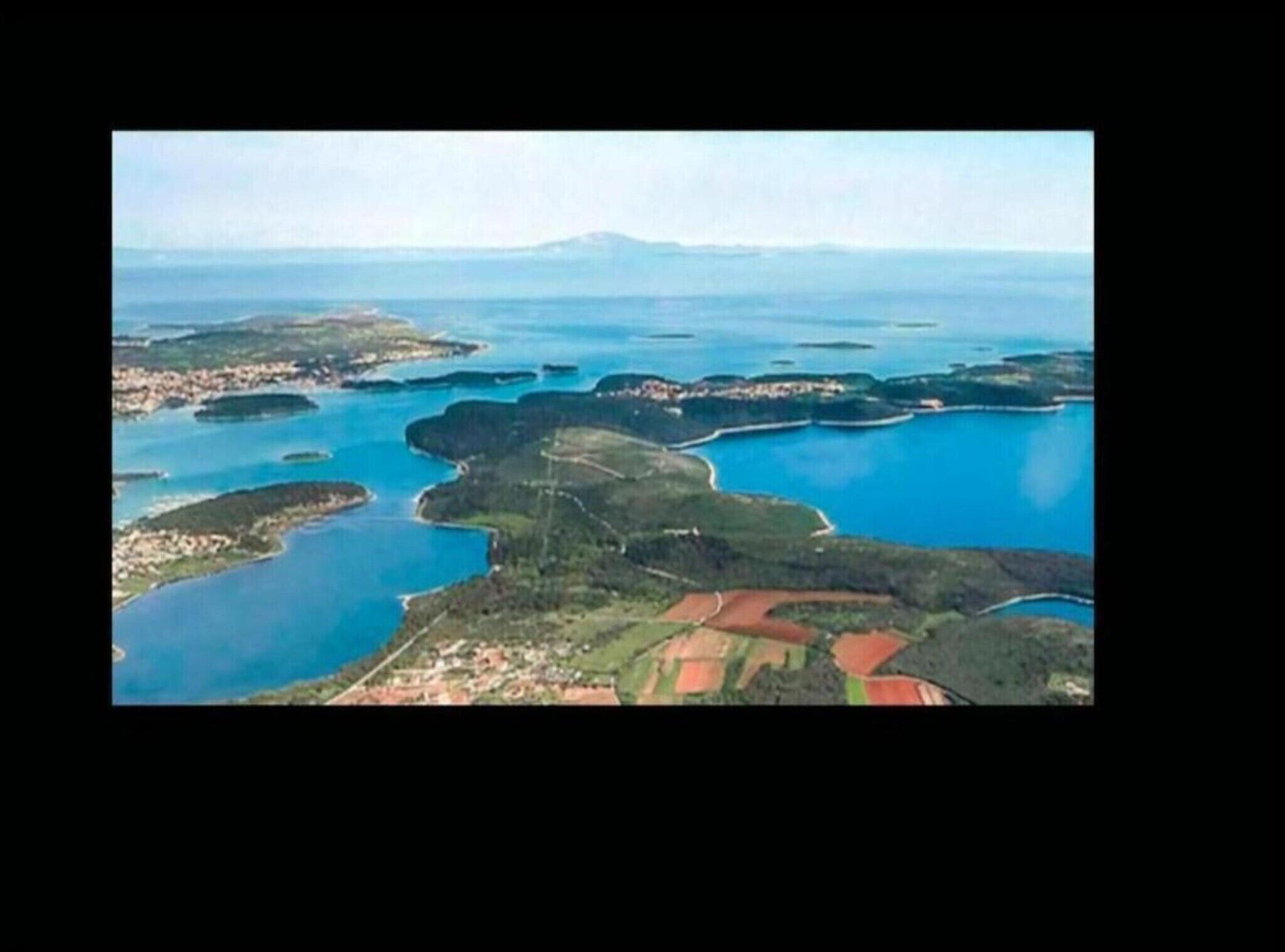 An aerial view of a coastal area with multiple islands connected by bridges, surrounded by blue waters.