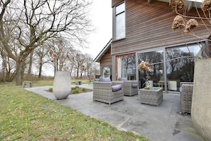 A modern house with a patio area featuring wicker furniture and a large planter.