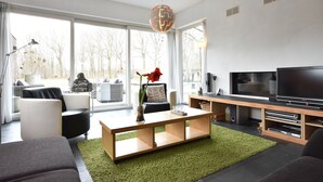 Un soggiorno moderno con una grande TV, posti a sedere comodi e vista sull'esterno.