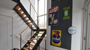 Una moderna scala con ringhiere nere e gradini in legno, che conduce a una stanza dal pavimento scuro.