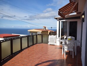 A balcony with a view of the ocean, a white chair, and a table with a bowl. - Holiday Home Mesa del Mar near Black Beach (Tacoronte)
