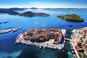 An aerial view of a coastal town with a central fortified area, surrounded by water and small islands.