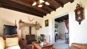 A living room with a television, sofa, leather chair, wooden coffee table, patterned rug, fireplace, and a clock on the wall. - Holiday Home in Decize near Beach (Decize)