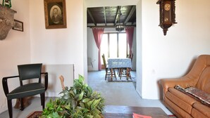 A cozy living room with a green chair, a brown sofa, a wooden table with a plant, and a dining area with a table and chairs. - Holiday Home in Decize near Beach (Decize)