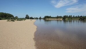 A riverbank with clear water, sandy shore, and dense greenery in the background. - Holiday Home in Decize near Beach (Decize)