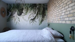 A bedroom with a brick wall, a mural of leaves, a geometric-patterned bedspread, and a hanging light fixture. - Luxurious Cottage in Aywaille with Sauna (Aywaille)