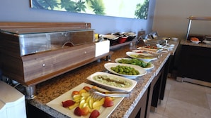 A buffet setup with various food items and a wooden cabinet. - Hitit Otel (Ankara)