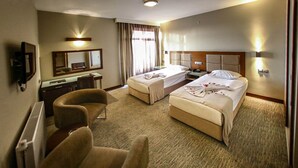 A hotel room with two beds, a desk, a chair, and a large mirror. - Hitit Otel (Ankara)