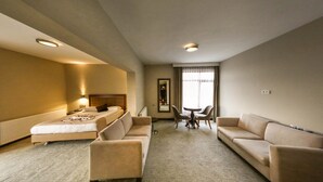 A hotel room with a bed, two sofas, a small table, and a chair. - Hitit Otel (Ankara)