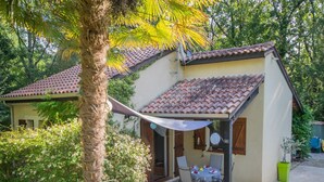 Une maison avec un toit en tuiles, un patio couvert avec une table et des chaises, et un espace piscine.